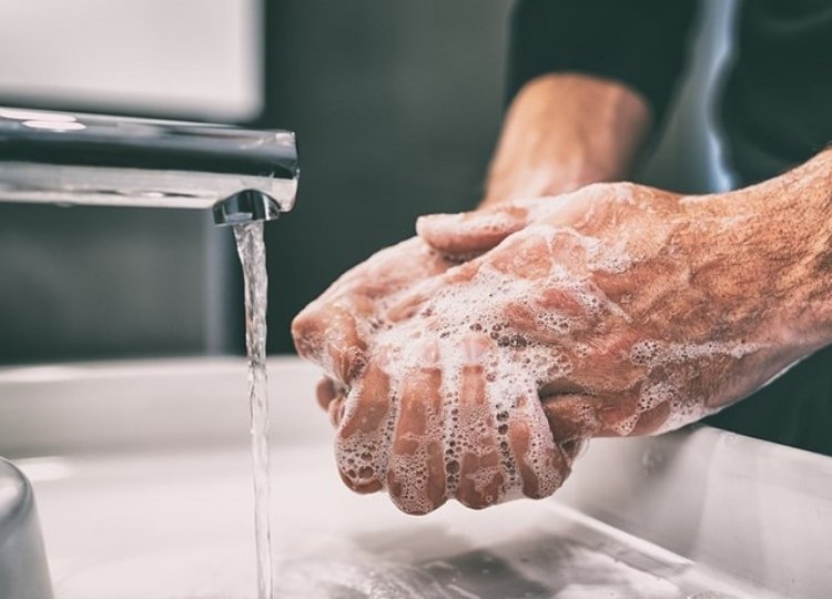 Man washing hands with soap and water on a faucet sink